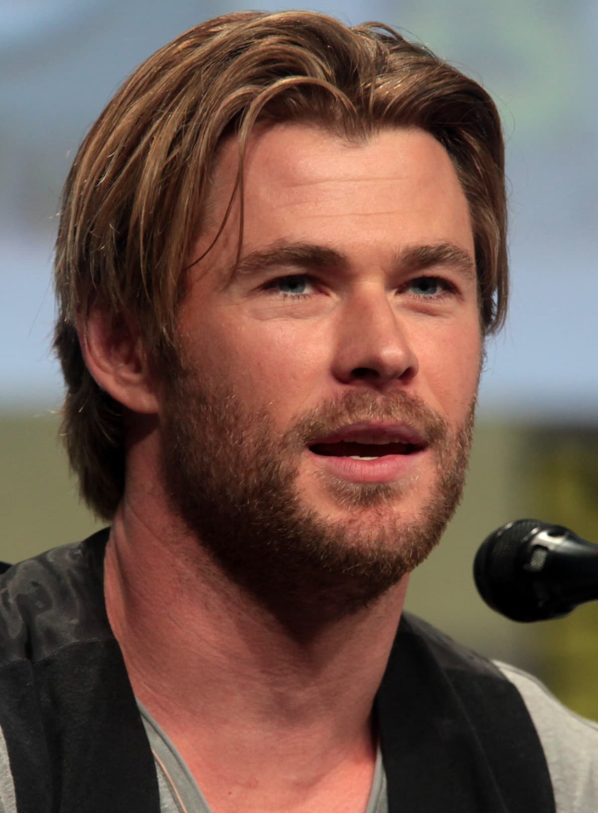 SDCC 2014 cropped frontal — blonde short crop, strong jaw, blue-eyed soft smile under convention flash.