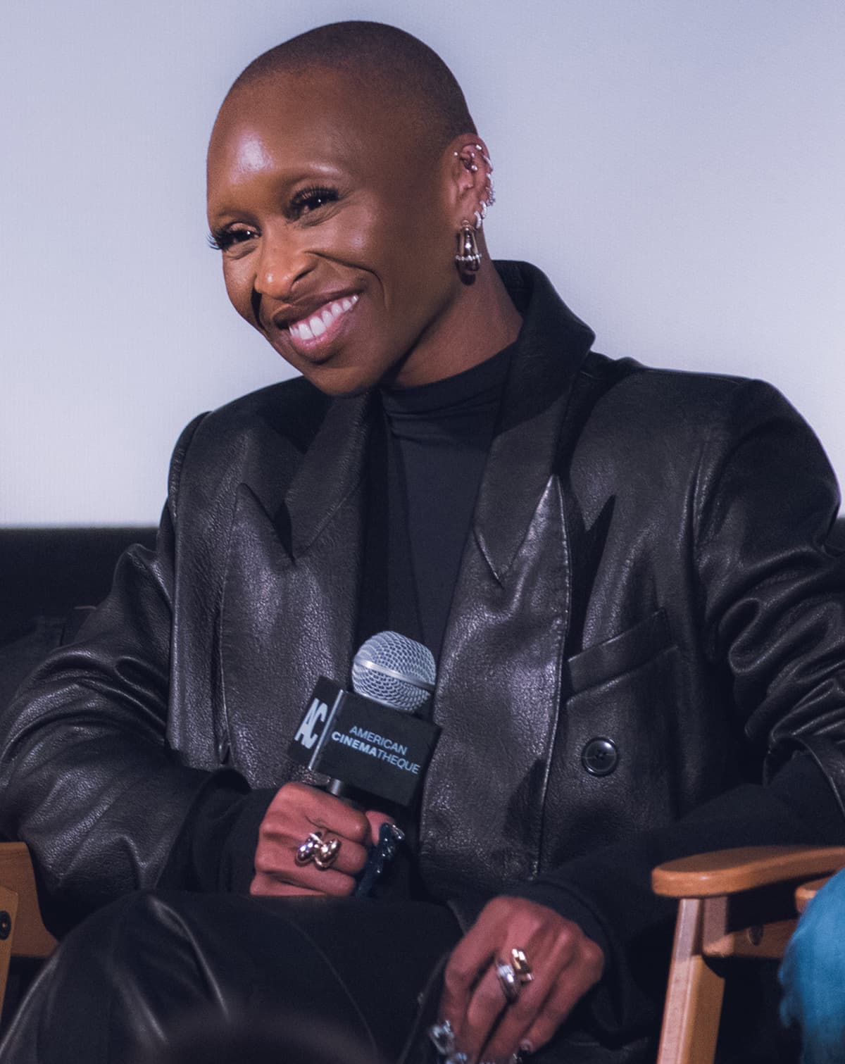Wicked FYC frontal — shaved-crop silhouette, strong brow, soft smile under studio key.