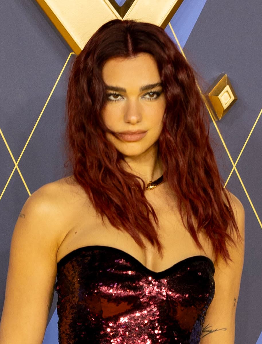 Premiere frontal — almond gaze, arched brows, sharp jaw under carpet flash.