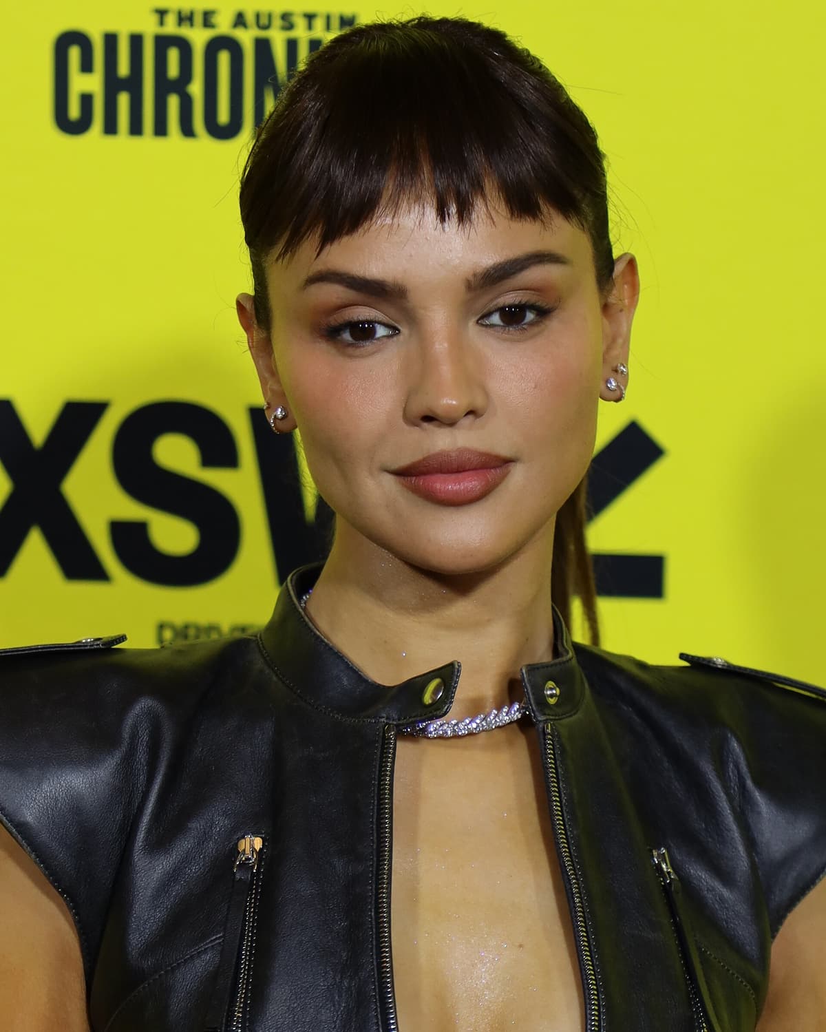 SXSW 2025 cropped frontal — dark waves, soft smile, warm olive undertones under festival key.