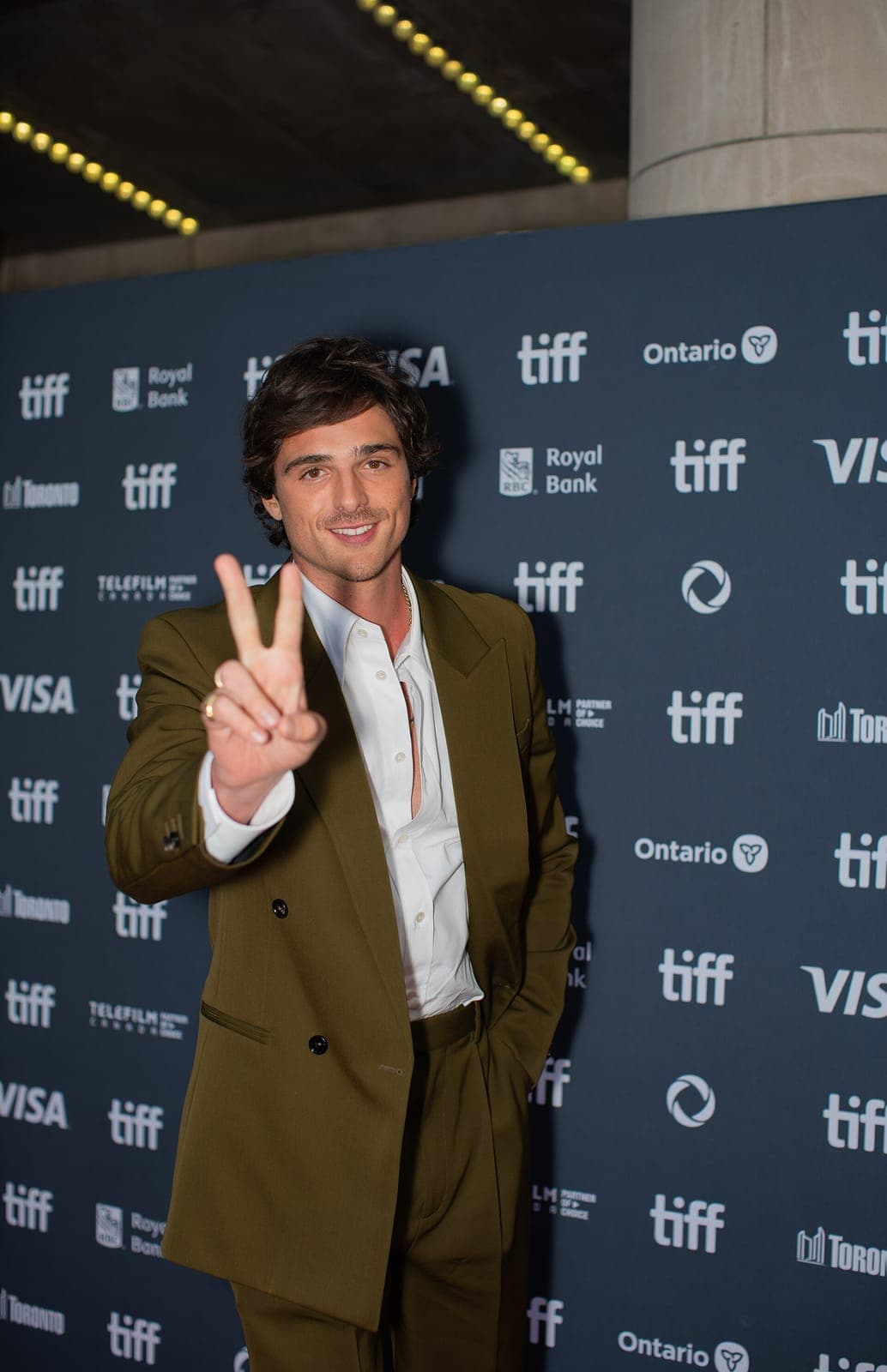 Later TIFF angle — soft-smile eras vs hard jaw silhouette under flash.