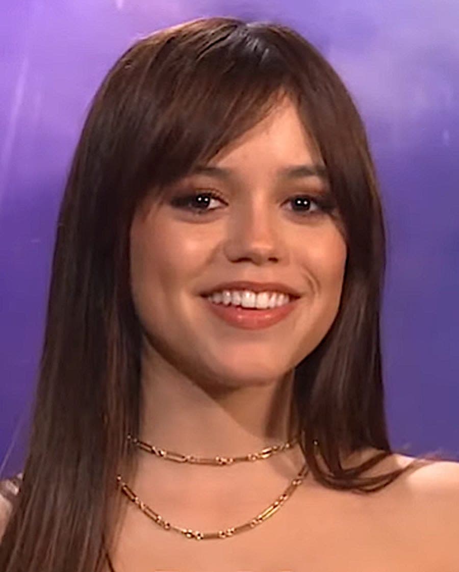 Vertical crop — dark hair frame, soft midface, gaze-forward under event light.