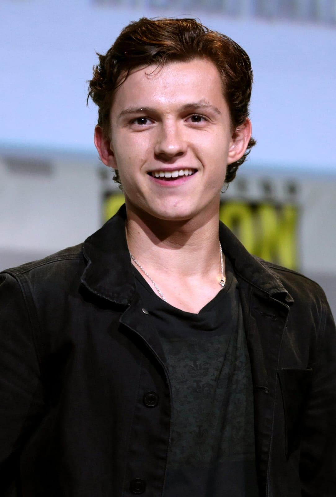 SDCC frontal — soft angular taper, warm brown gaze, short brown temple control under convention flash.